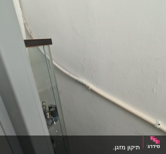צינור לבן על קיר ליד ארון זכוכית